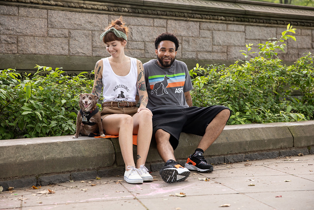 a woman and man sitting with a rat terrier in the park