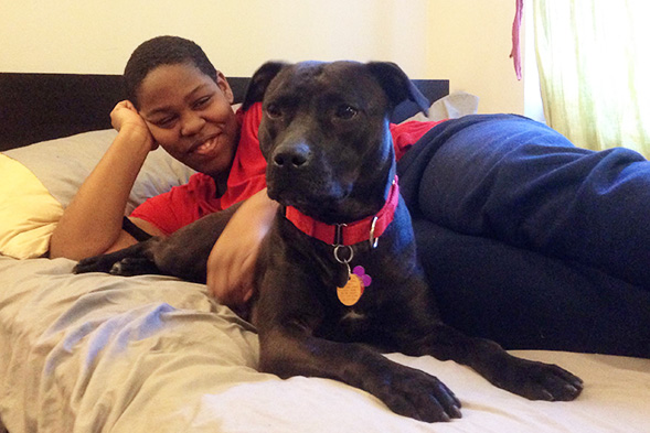 Young man lounging on bed with black dog