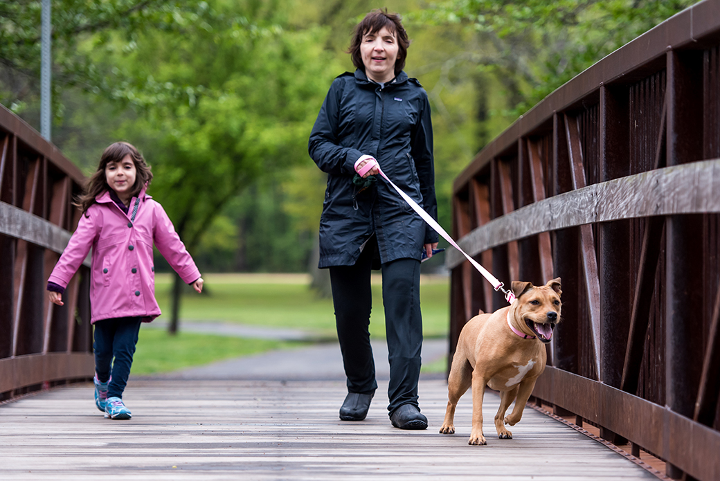 a woman walking a dog with her daughter over a bridge