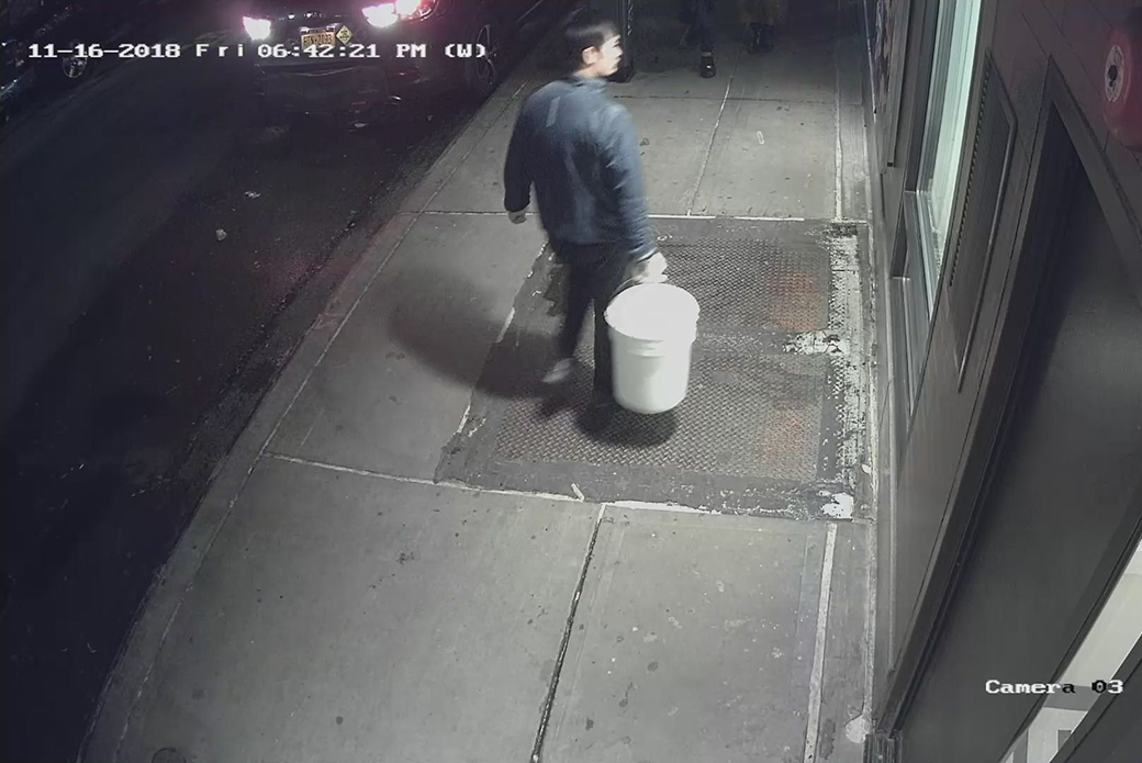 suspect carrying a sealed bucket with a cat in it