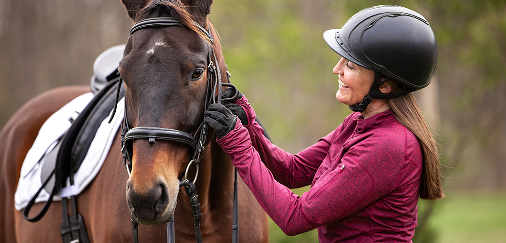 a woman adjusting a horse's harness