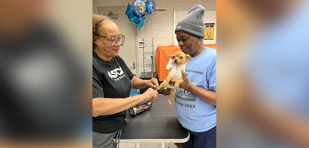 A woman holding her dog while ASPCA staff gives it a vaccine