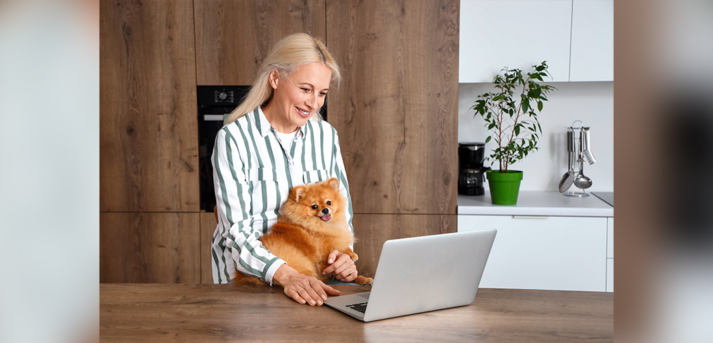A woman with a pomeranian at a laptop