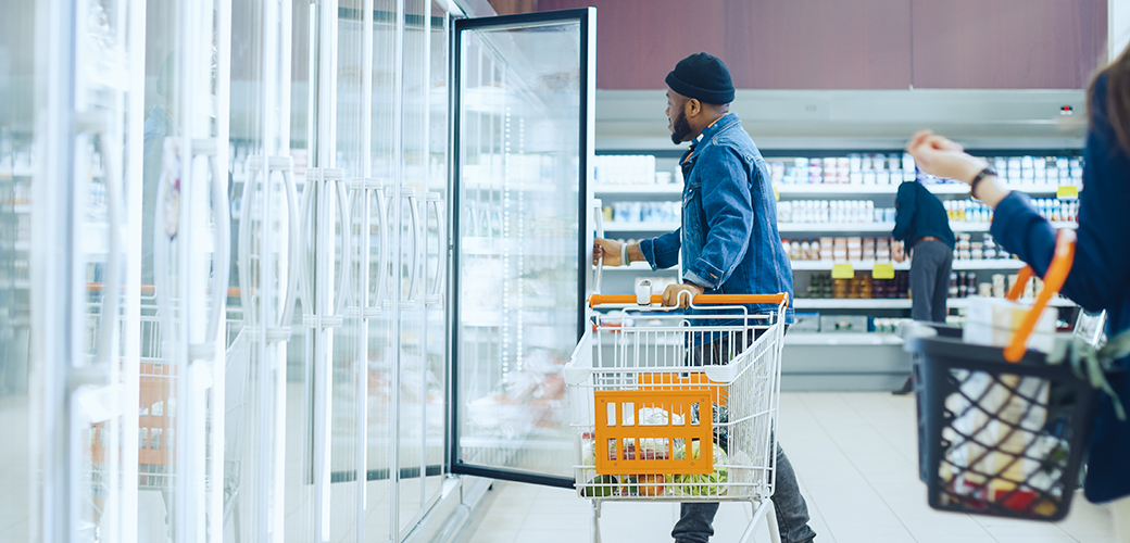 A man looking into a refrigerator at the grocery story