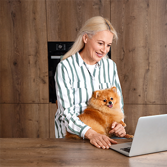 A woman with a pomeranian at a laptop