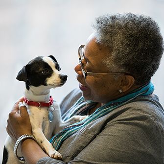 a woman holding a small brown and white dog