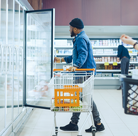 A man looking into a refrigerator at the grocery story